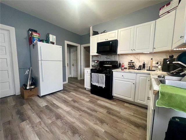 kitchen with black appliances, white cabinetry, sink, backsplash, and light wood-type flooring