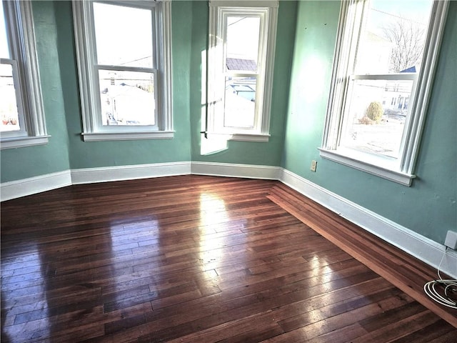 spare room with plenty of natural light and dark hardwood / wood-style floors