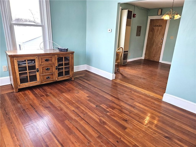 spare room with dark hardwood / wood-style floors and a chandelier