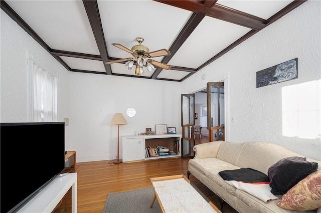 living room with light wood-type flooring, ceiling fan, beam ceiling, and coffered ceiling