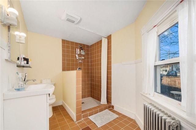 bathroom featuring toilet, a tile shower, tile patterned flooring, radiator, and vanity