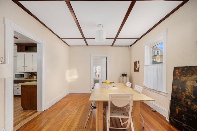 dining space with coffered ceiling and light wood-type flooring