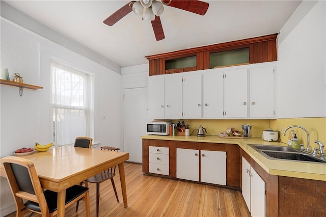 kitchen with ceiling fan, backsplash, light hardwood / wood-style floors, sink, and white cabinetry