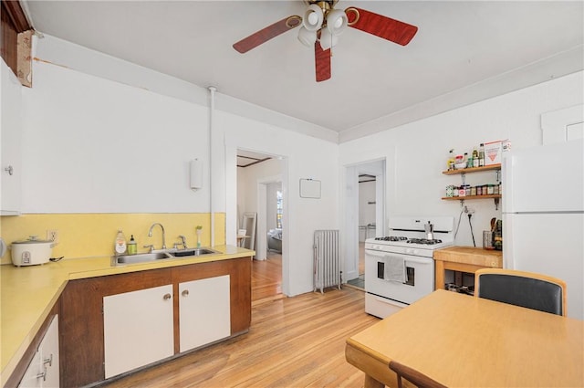 kitchen with sink, white appliances, light wood-type flooring, white cabinets, and radiator heating unit