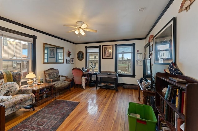 living area with ceiling fan, wood-type flooring, crown molding, and a healthy amount of sunlight