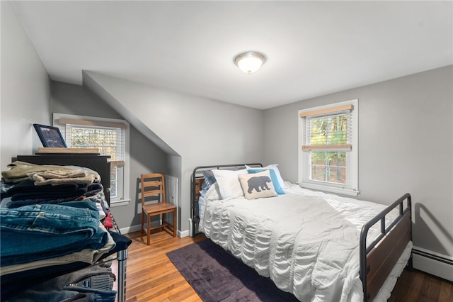 bedroom with baseboard heating and hardwood / wood-style floors