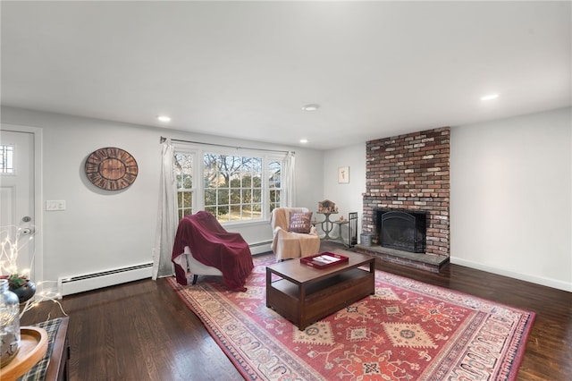 living room with dark wood-type flooring, a baseboard radiator, and a fireplace