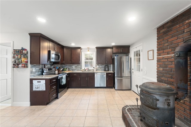 kitchen with dark brown cabinetry, stainless steel appliances, tasteful backsplash, sink, and light tile patterned floors