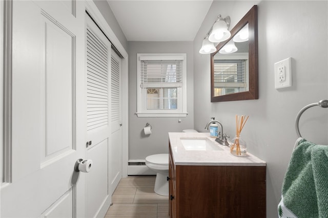 bathroom with toilet, vanity, and baseboard heating