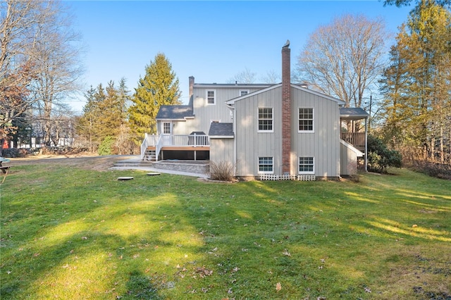 back of house featuring a lawn and a deck