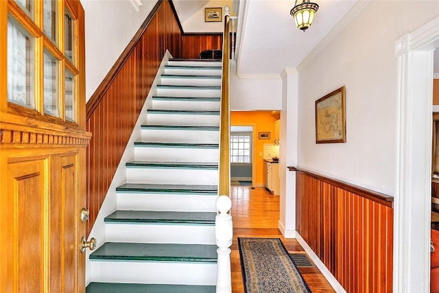 staircase featuring wood-type flooring and ornamental molding