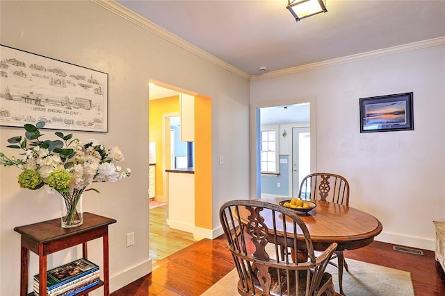 dining space featuring ornamental molding and hardwood / wood-style flooring