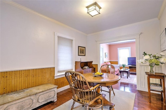 dining area with wood walls, dark wood-type flooring, and crown molding