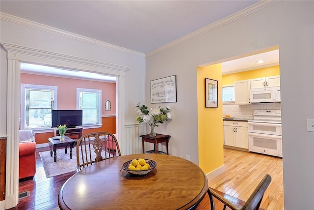 dining space with crown molding and light wood-type flooring