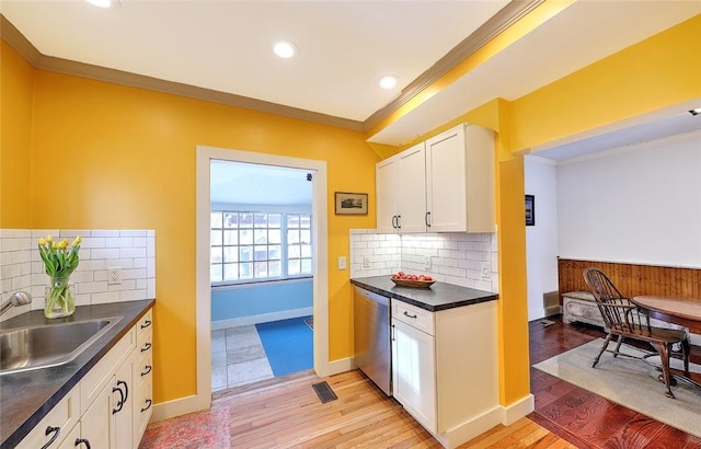 kitchen featuring tasteful backsplash, dishwasher, sink, crown molding, and white cabinetry