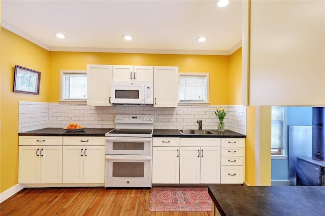 kitchen with a wealth of natural light, sink, white cabinets, and white appliances