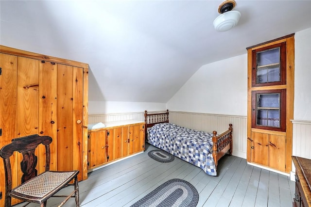 bedroom with dark hardwood / wood-style floors, lofted ceiling, and wooden walls