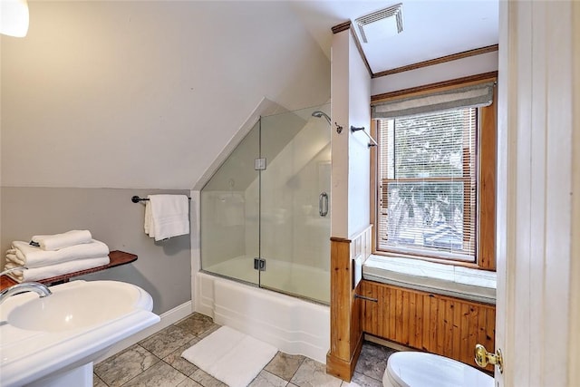 bathroom with toilet, enclosed tub / shower combo, vaulted ceiling, and wooden walls