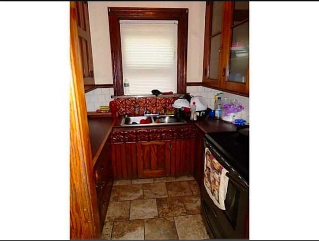 kitchen with sink, black range with electric stovetop, decorative backsplash, and washer / dryer