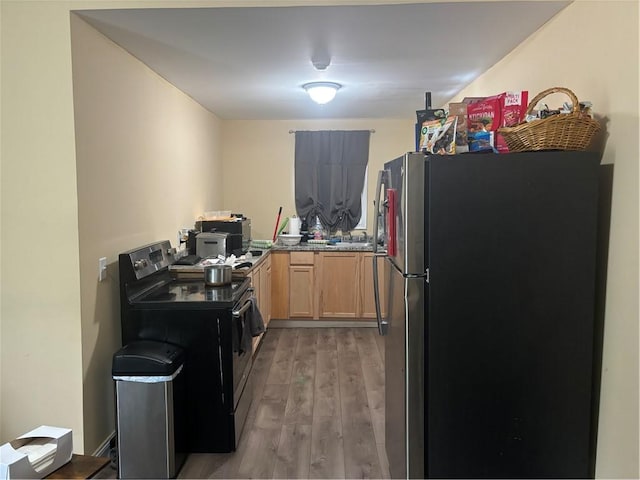 kitchen featuring electric range, stainless steel fridge, light brown cabinets, and light wood-type flooring