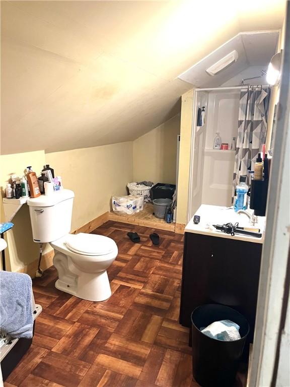 bathroom featuring toilet, a shower with shower curtain, parquet floors, vaulted ceiling, and vanity