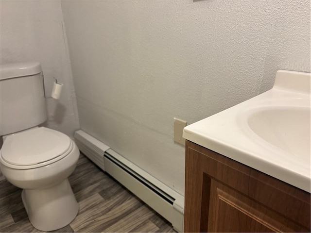 bathroom featuring a baseboard heating unit, toilet, hardwood / wood-style floors, and vanity