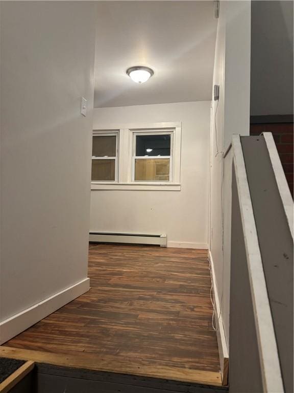 hallway with a baseboard heating unit and dark hardwood / wood-style floors