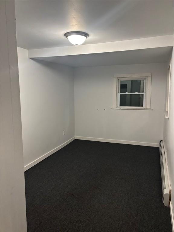 carpeted spare room featuring a baseboard heating unit