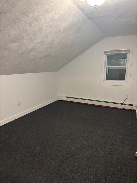 bonus room featuring lofted ceiling, carpet floors, a textured ceiling, and a baseboard radiator