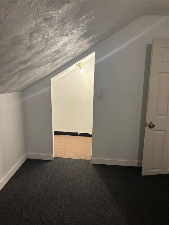 additional living space with lofted ceiling, dark carpet, and a textured ceiling