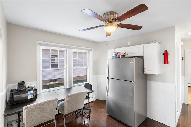 kitchen featuring ceiling fan, white cabinetry, stainless steel refrigerator, and a baseboard heating unit