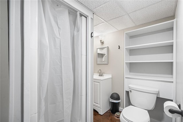 bathroom featuring toilet, a paneled ceiling, and vanity