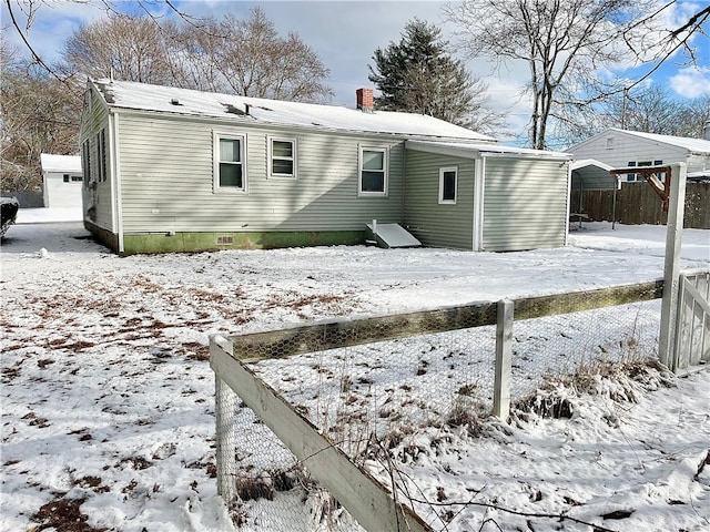 snow covered back of property featuring a carport