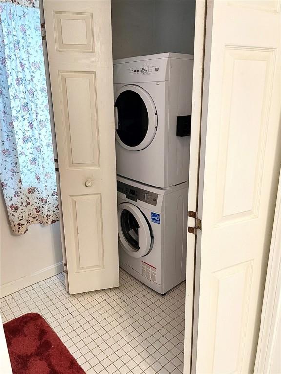 laundry room with light tile patterned floors and stacked washing maching and dryer