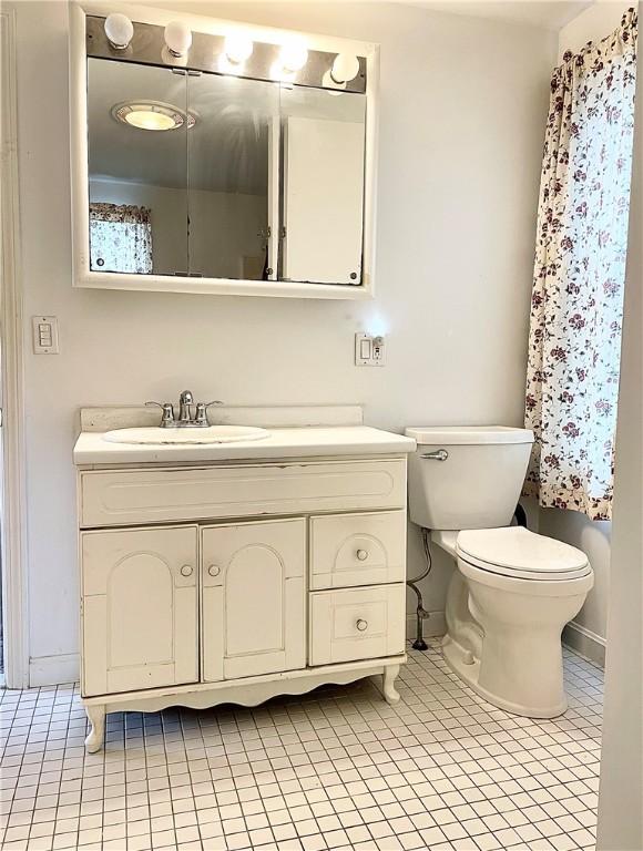 bathroom with toilet, vanity, and tile patterned floors