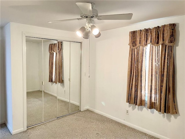 unfurnished bedroom featuring ceiling fan, a closet, and light carpet