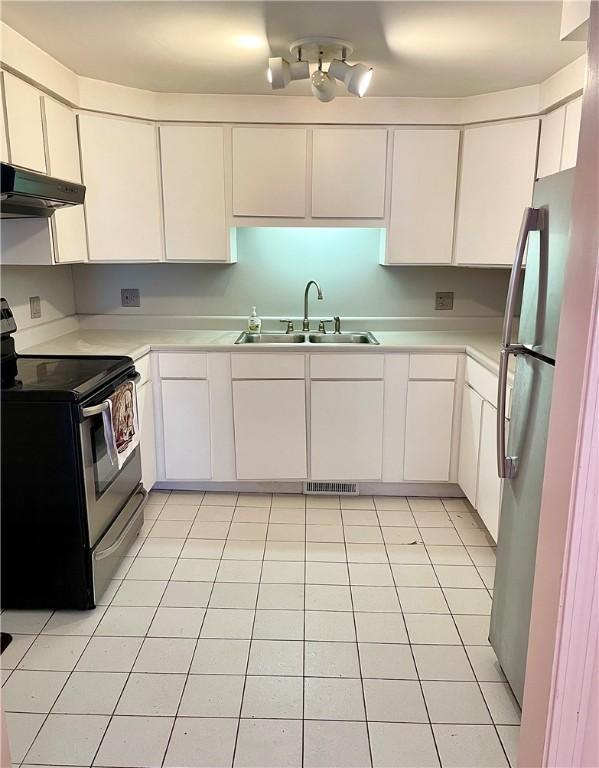 kitchen featuring white cabinets, sink, light tile patterned floors, and stainless steel appliances