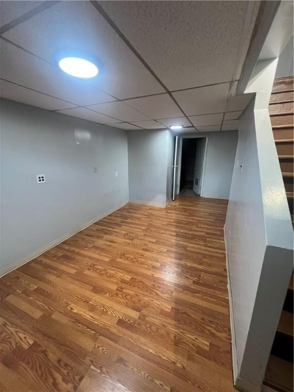 basement with hardwood / wood-style floors and a paneled ceiling