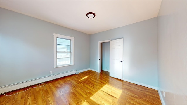 unfurnished bedroom featuring baseboard heating and light hardwood / wood-style floors