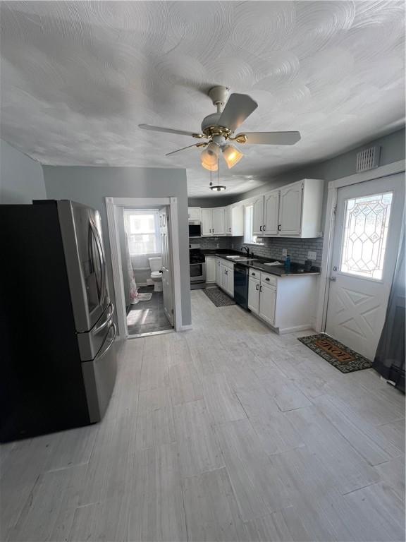 kitchen with sink, white cabinetry, appliances with stainless steel finishes, ceiling fan, and backsplash