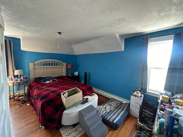 bedroom featuring lofted ceiling, multiple windows, wood-type flooring, and baseboard heating