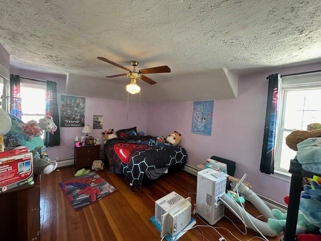 bedroom with a textured ceiling, wood-type flooring, a baseboard radiator, and ceiling fan