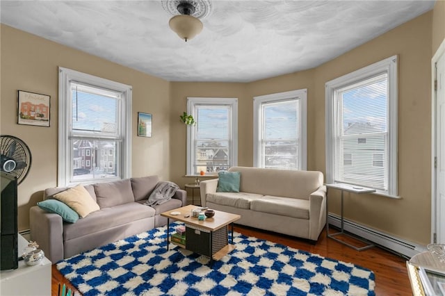 living room with baseboard heating, dark hardwood / wood-style floors, and plenty of natural light