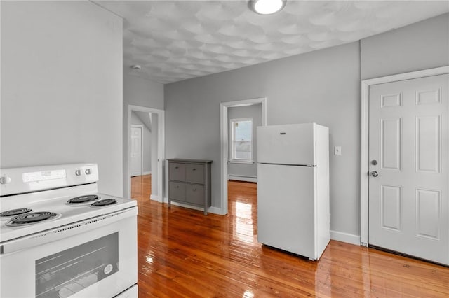 kitchen with baseboard heating, light hardwood / wood-style floors, and white appliances