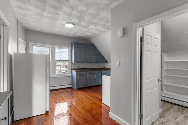 kitchen with a baseboard heating unit, white refrigerator, gray cabinetry, and light wood-type flooring