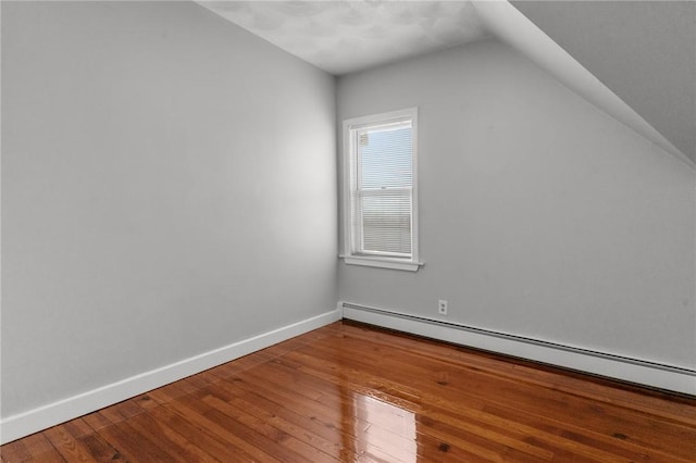 additional living space featuring a baseboard heating unit, vaulted ceiling, and wood-type flooring