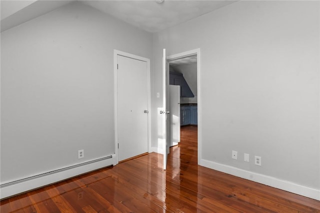 unfurnished room featuring a baseboard heating unit and wood-type flooring