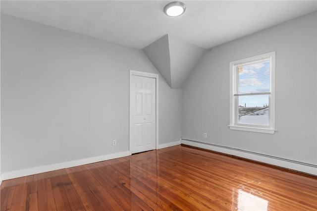 additional living space featuring baseboard heating, wood-type flooring, and lofted ceiling