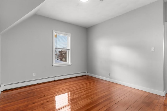 additional living space featuring vaulted ceiling, baseboard heating, and hardwood / wood-style flooring