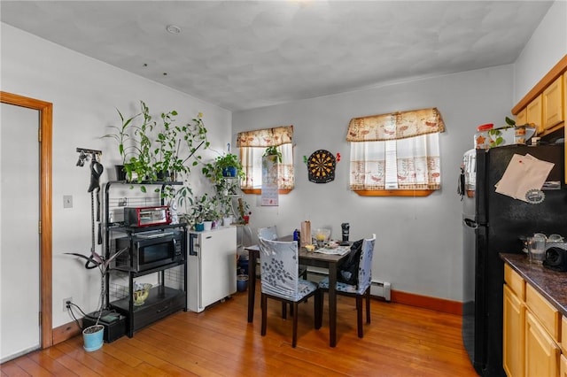 dining space with light hardwood / wood-style flooring and a baseboard radiator